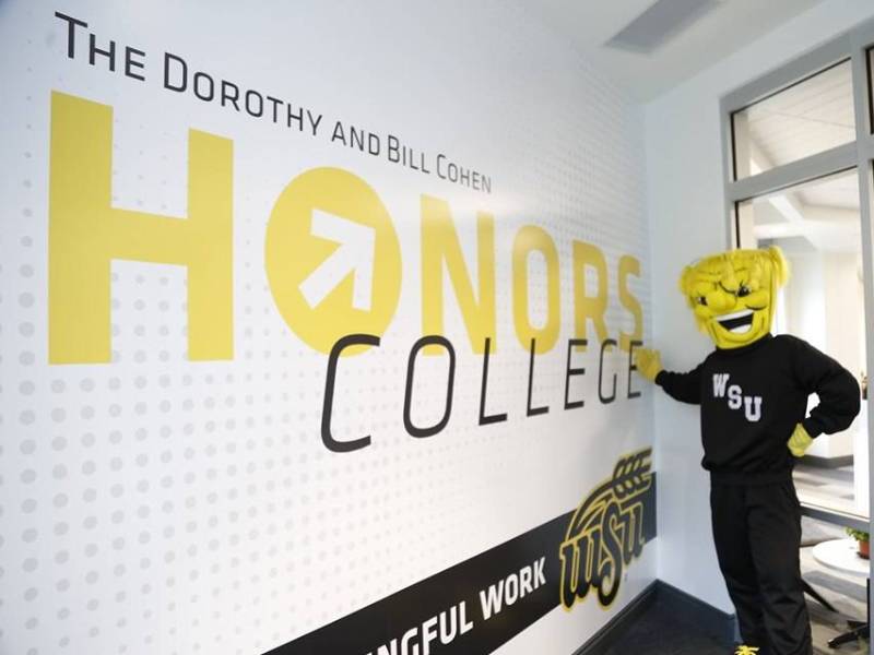 WU Shock standing in front of wall that reads Cohen Honors College More Meaningful Work