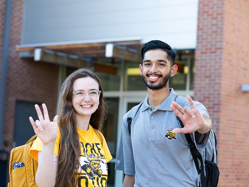 Two Honors Ambassadors making the WSU hand sign.