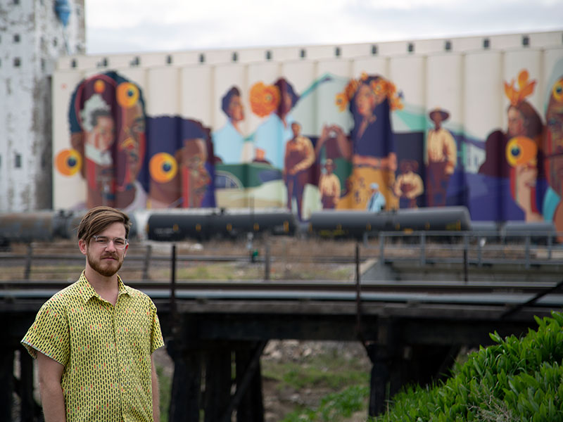 Art History and Honors College student Dale Small, pictured with the community mural he art directed