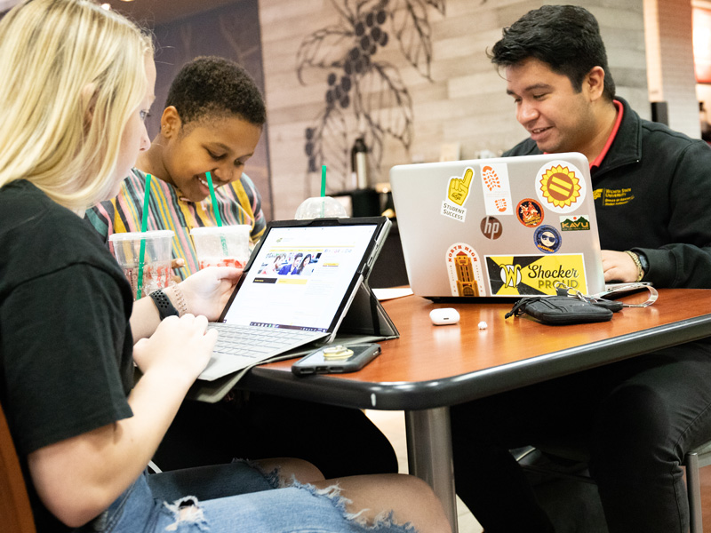 Three students working on computers seated by the Starbucks in the Rhatigan Student Center.