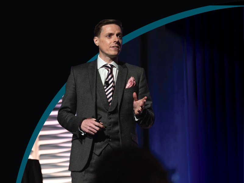 James Taylor standing on a stage presenting