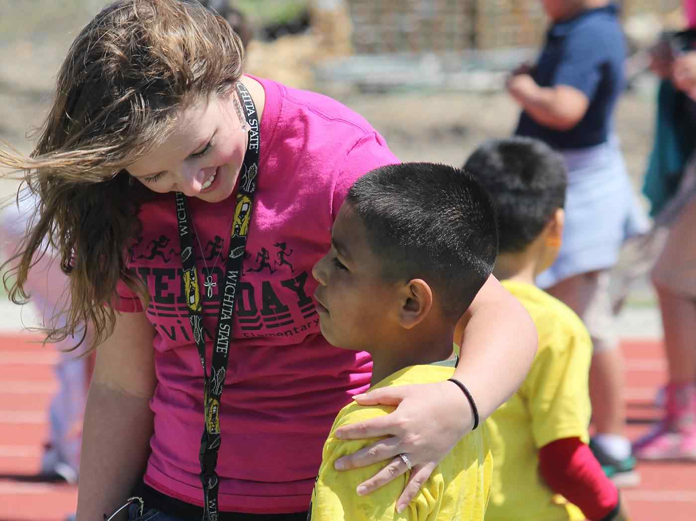 Female student teacher hugging student at recess.