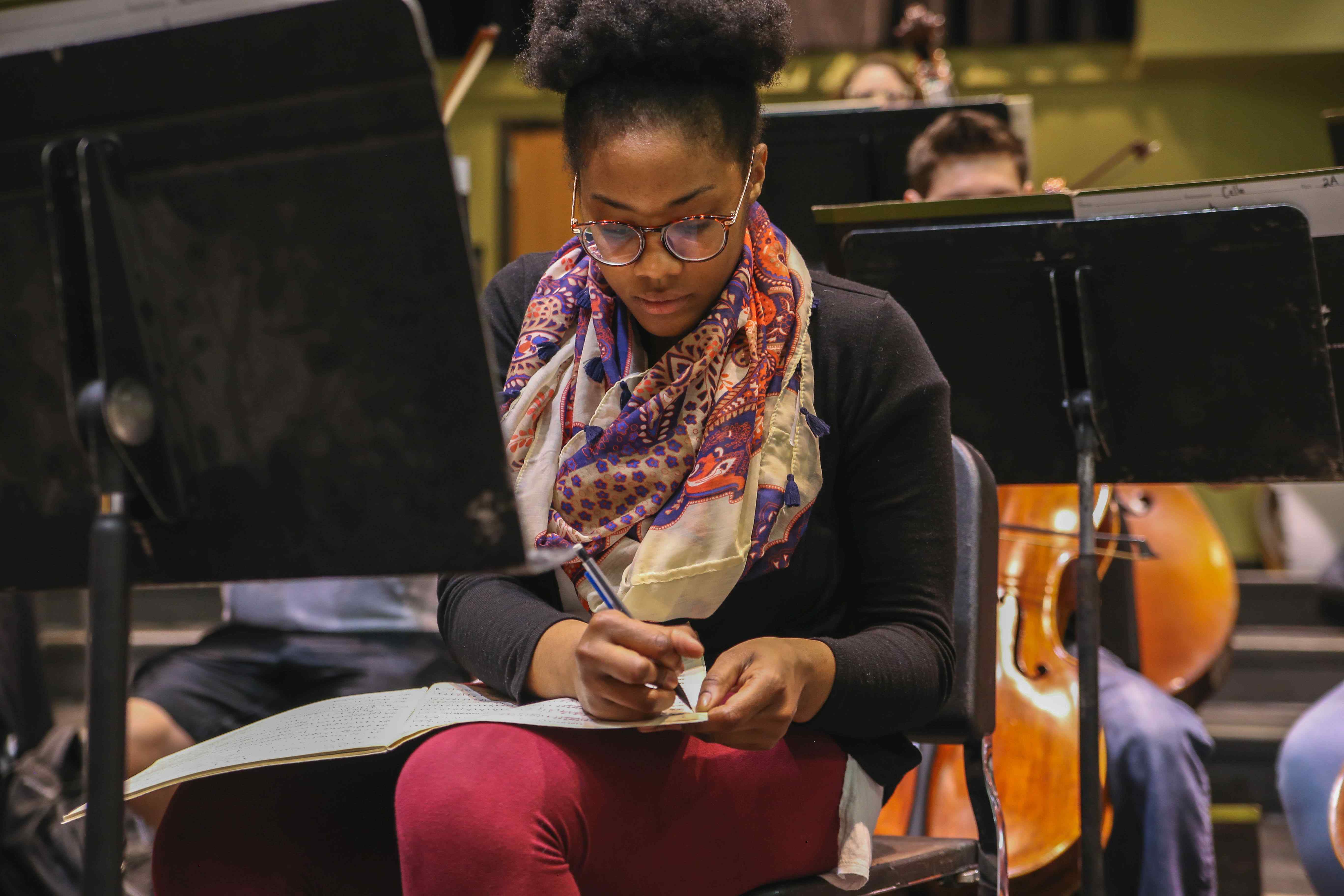 Music student adding a note to sheet music