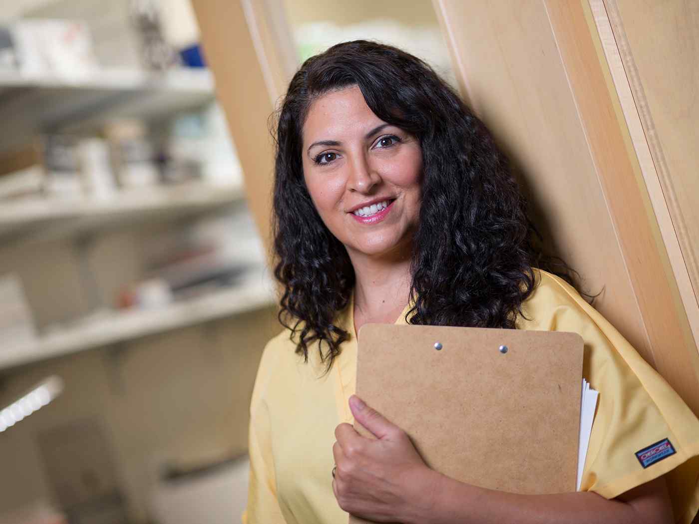 Nurse in yellow scrubs holds paperwork