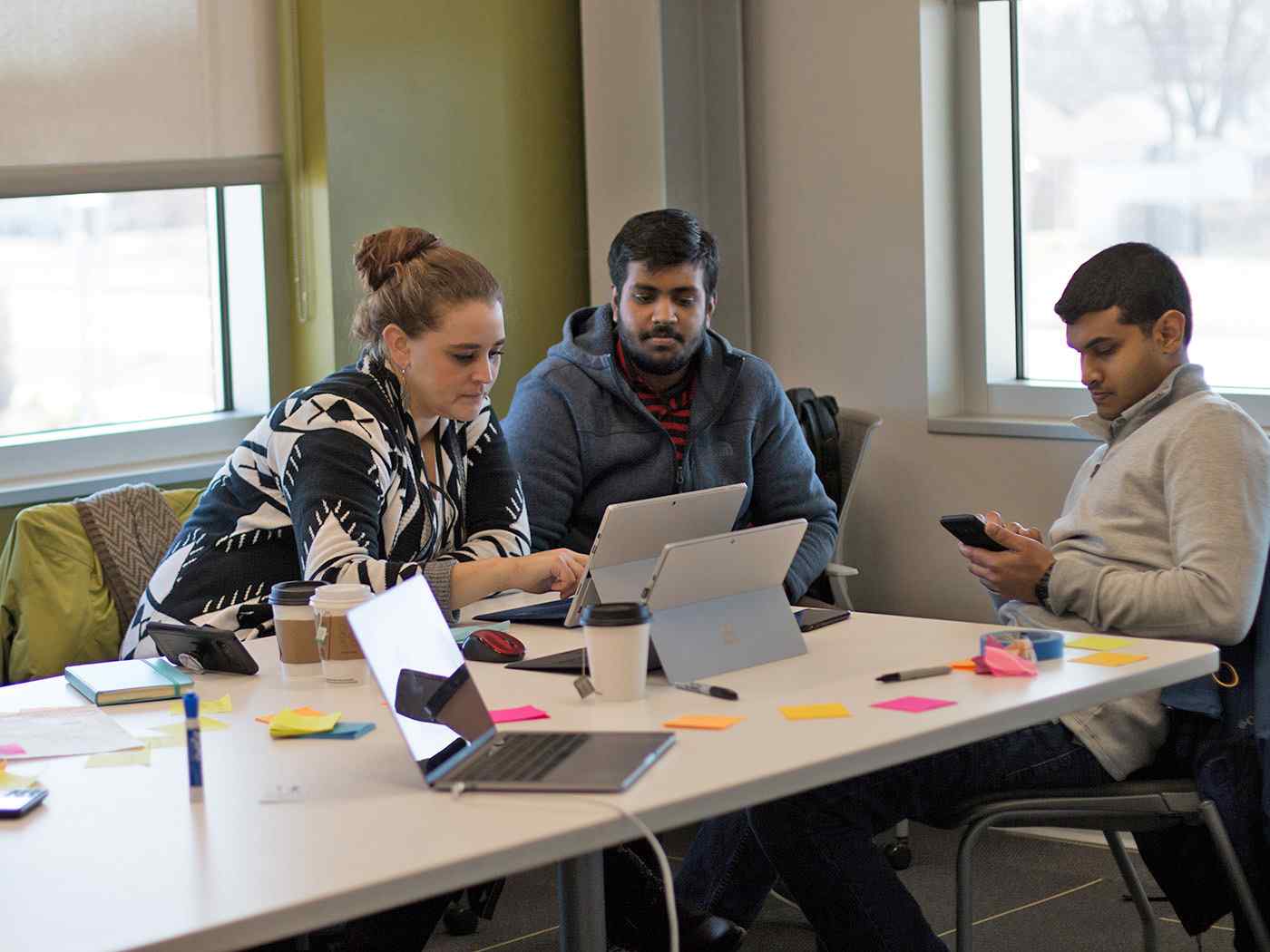 Computer Science students gathered around a table working on a project. 