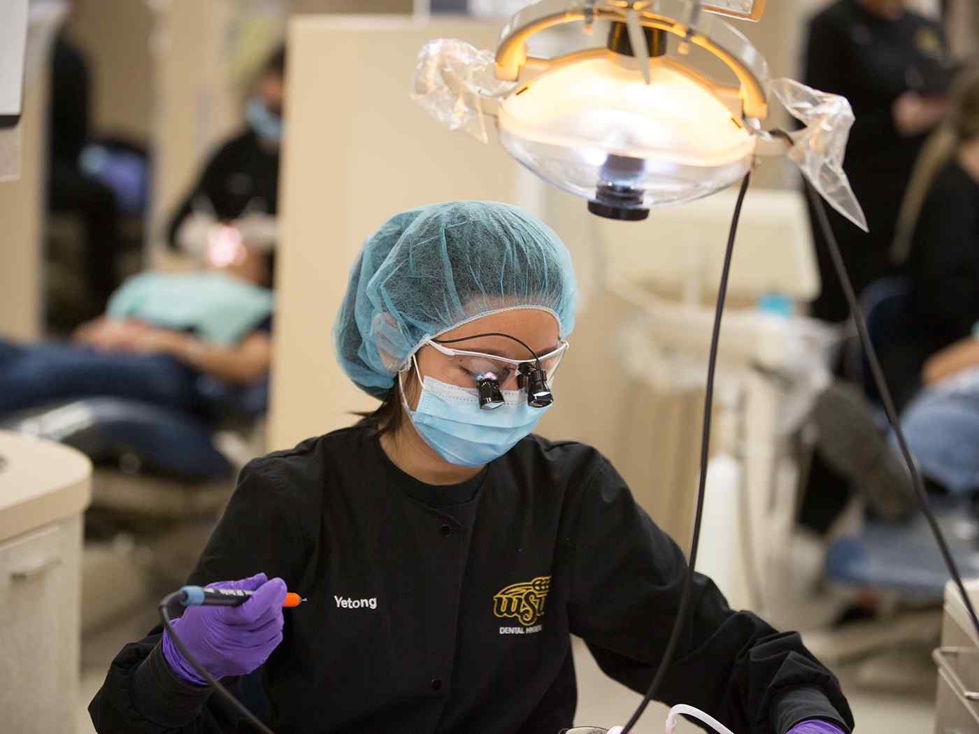 A dental hygien student works at an operatory