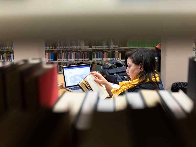 Adult learning female reading in library.