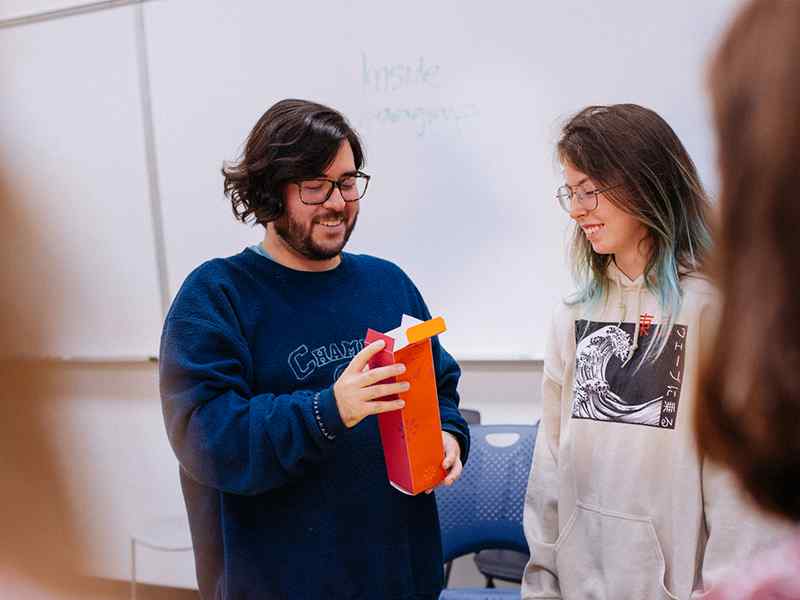 Graphic design students examine a packaging prototype in the classroom