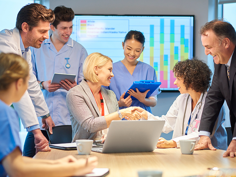 A small group of health care professionals meets in front of a graph