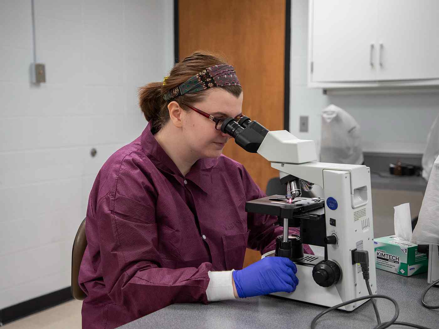 A student examines a sample under a microscope