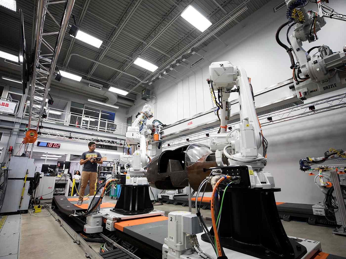 Mechatronics student standing in a large robotics lab. 