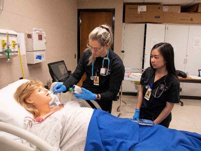 Two nursing students working with a mannequin