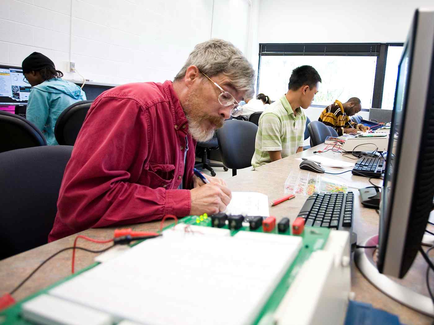 students working with a number of electrical devices and taking notes. 