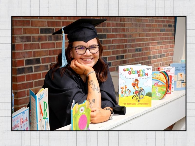 Jana smiling at the camera surrounded by children books