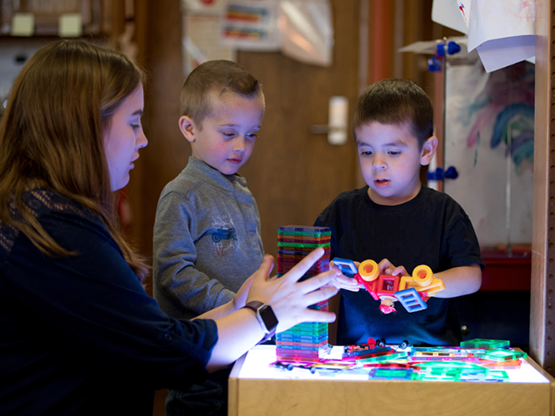 teacher in classroom helping two small children