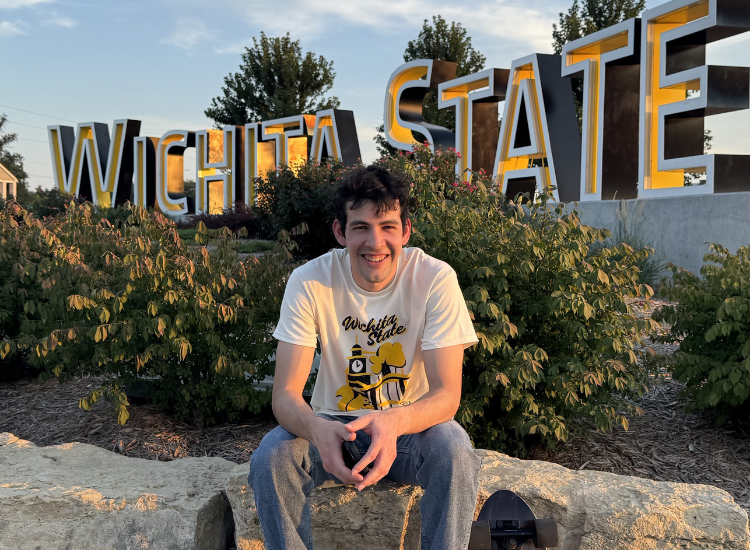 Fernando sitting in front of Wichita State sign