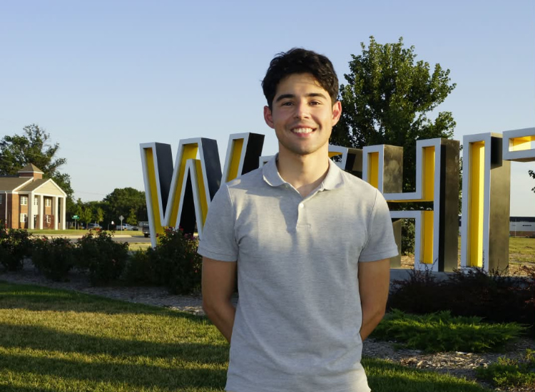 Jeremias in front of Wichita State sign