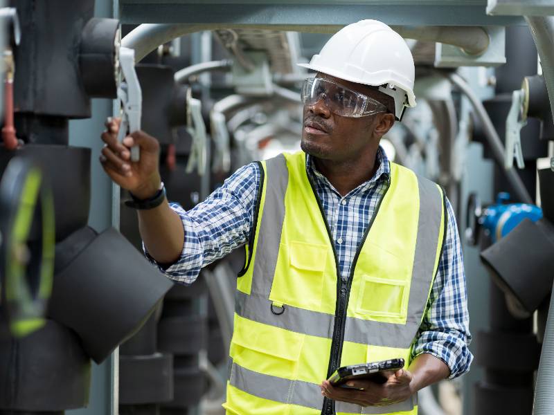 African American male engineer worker checks pipe network system at construction site