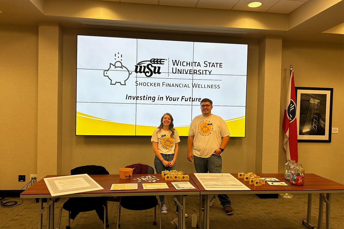 Two SFW student employees standing in front of a presentation.