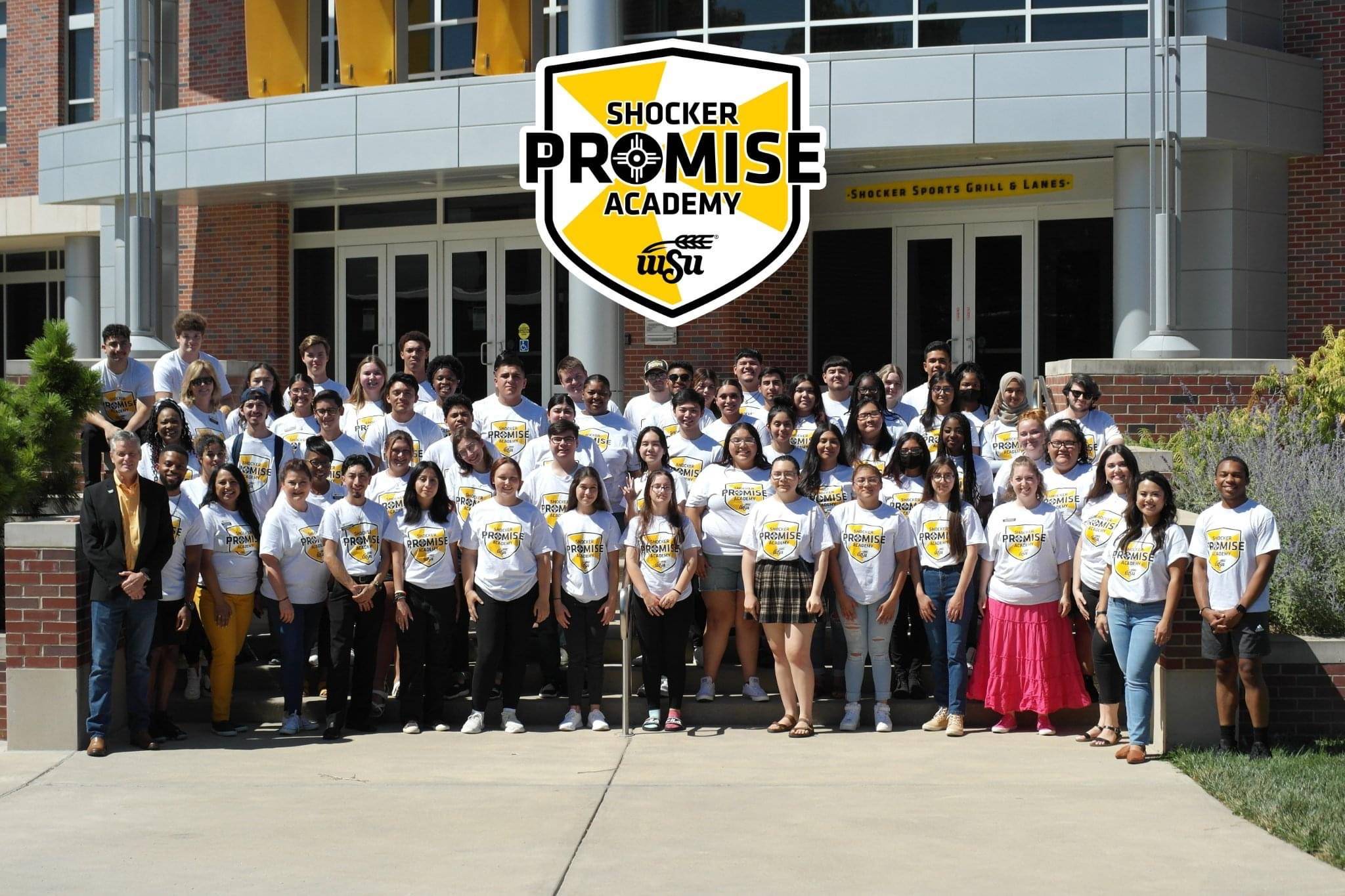 Students from the Shocker Promise Academy standing with President Muma at a building on campus