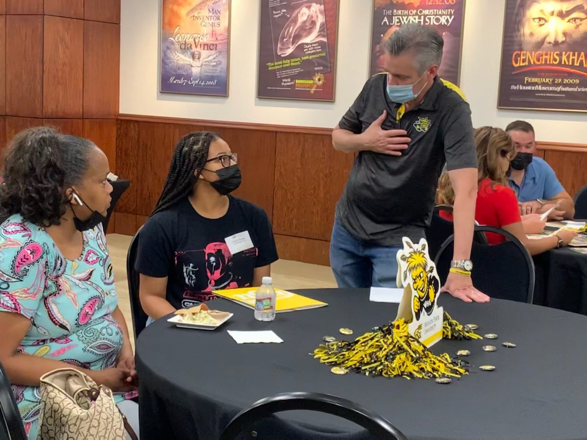 WSU President Rick Muma talks with high school students at a Houston recruiting event.