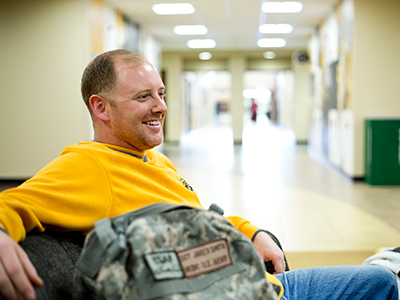 A student wearing a shocker polo relaxes in the RSC with their military backpack in the foreground
