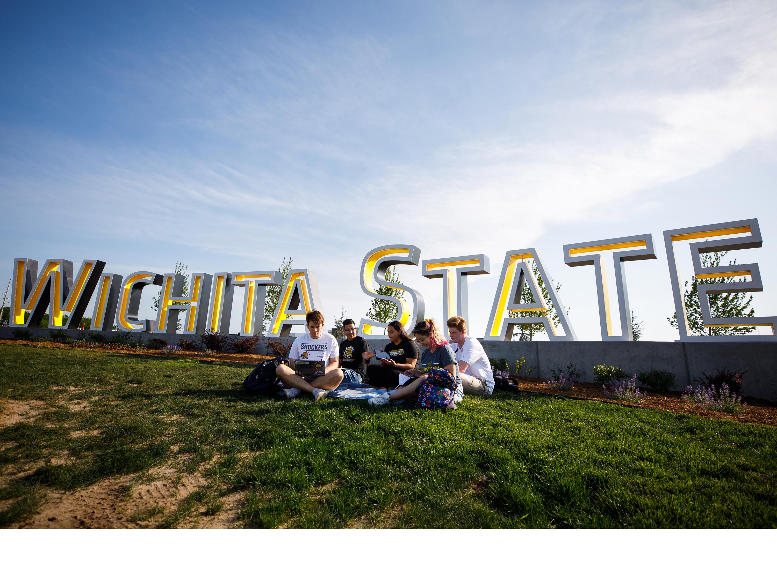 Students gather in front of the Wichita State sign at 21st and Oliver