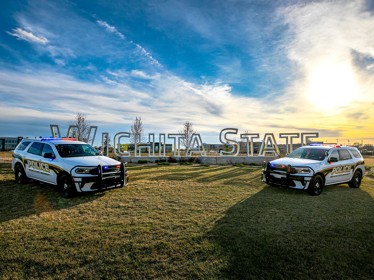 WSU PD cruisers in front of the Wichita State sign.