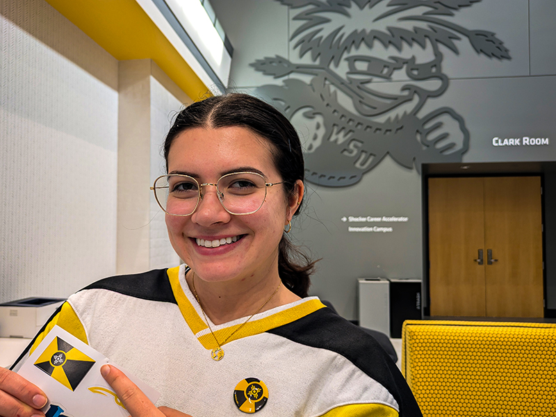 Nikky Bloomquist, Campus Visit Specialist, shows off a Wichita flag sticker and button.
