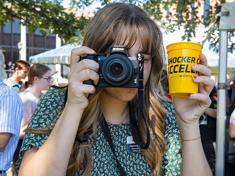 Jenna Rodehorst, Marketing Coordinator, with her camera at the 2024 Shocker Career Accelerator Root Beer Kegger.