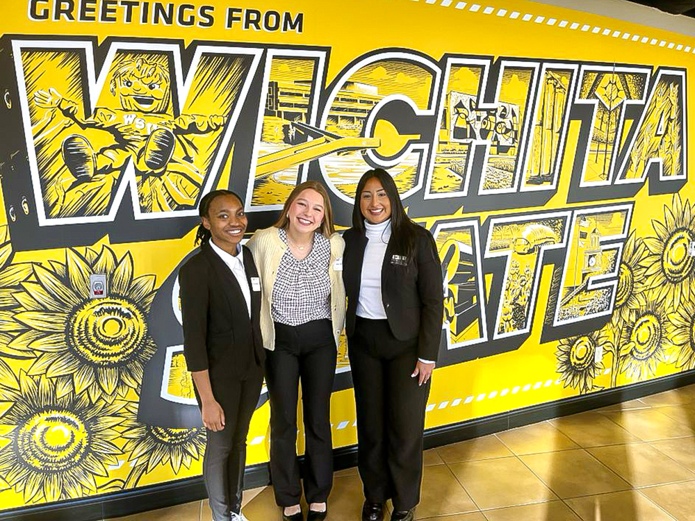 Jayden Island, Maley Hansen and Lesly Hernandez, 2023 Gore Scholars, pose for a photo in front of the Wichita State mural in the Rhatigan Student Center.