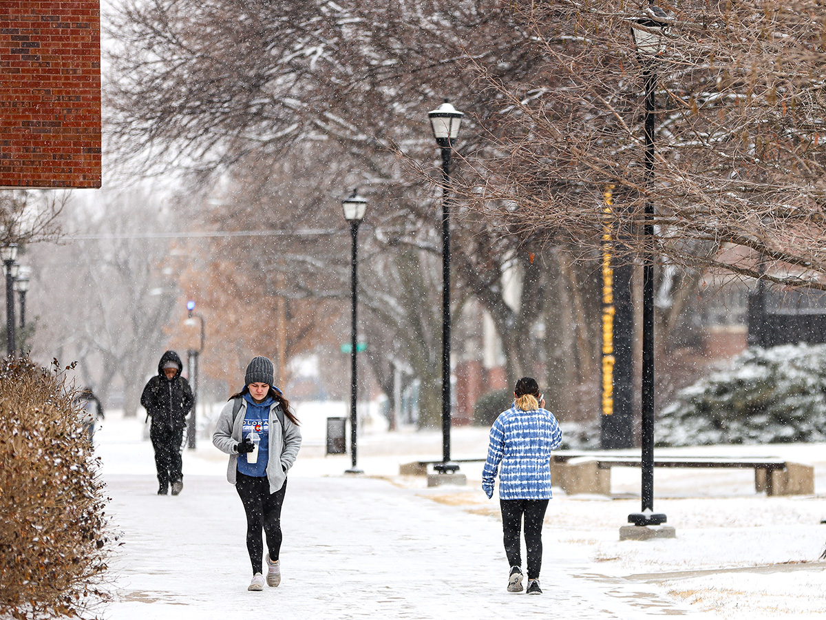 Students walking on a snowy campus day.