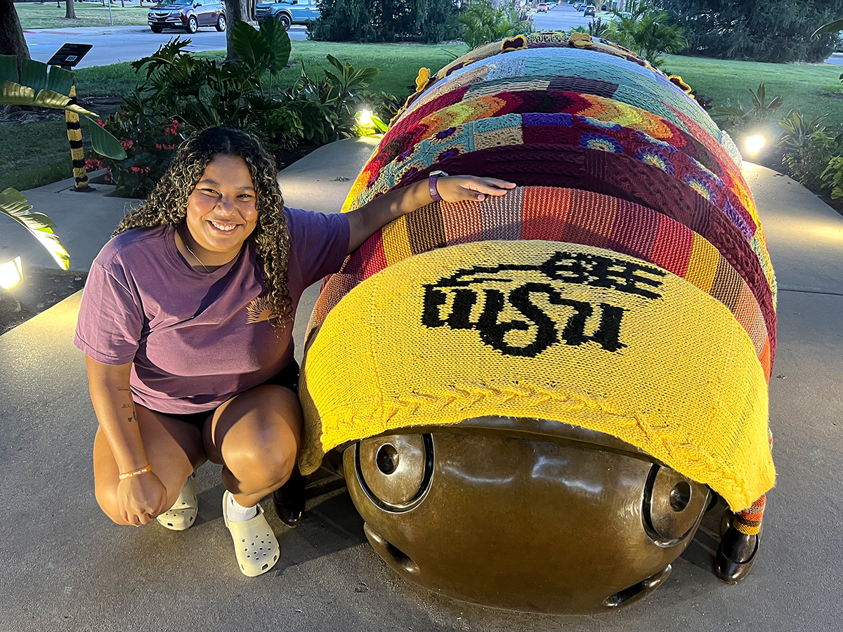Analiz Rivas taking a photo with "Millie" the millipede sculpture at Wichita State.