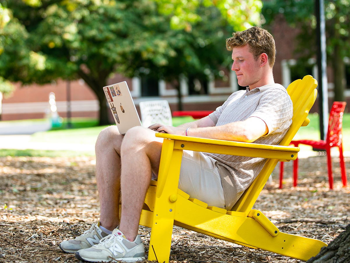 Student using one of Wichita State's outdoor chairs on a nice day.