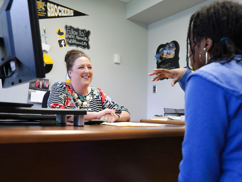 Student sitting across a desk from an advisor