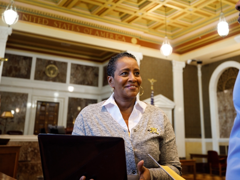 Professional stands in courthouse and has conversation with the courthouse clerk.