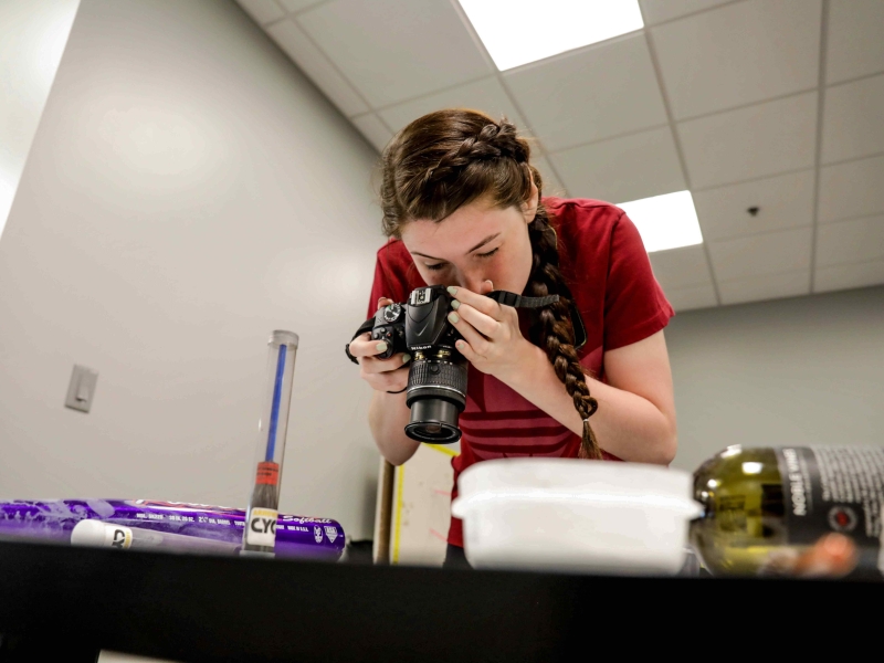 Student photographs evidence in a mock crime scene setup.