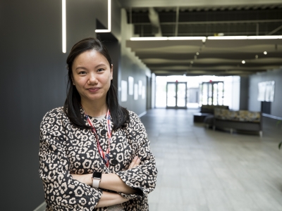 Person stands in a hallway and looks confidently into camera.