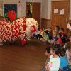 A large group of children watch a Chinese dragon dance.