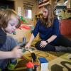 A staff member helps a child assemble train tracks.