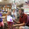 Staff member discusses a child's painting in front of the class.