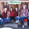 Staff members smile in red and black plaid clothing for lumberjack day.