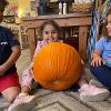 A child poses with a pumpkin