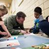 A staff member helps a child with arts and crafts.