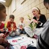 A staff member shows children the diagram of a flower.