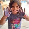 A child shows their hands after an art activity