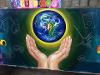 A painting of hands reaching out to the planet earth.