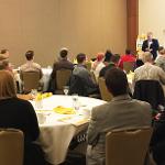 People sitting and listening to a presentation after eating breakfast.