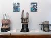 Two paintings, each depicting a mother and child, hang above three ceramic sculptures that look a little like decaying structures surrounded by metal armature. 