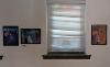 Three framed photographs of flowers hang on either side of a window.